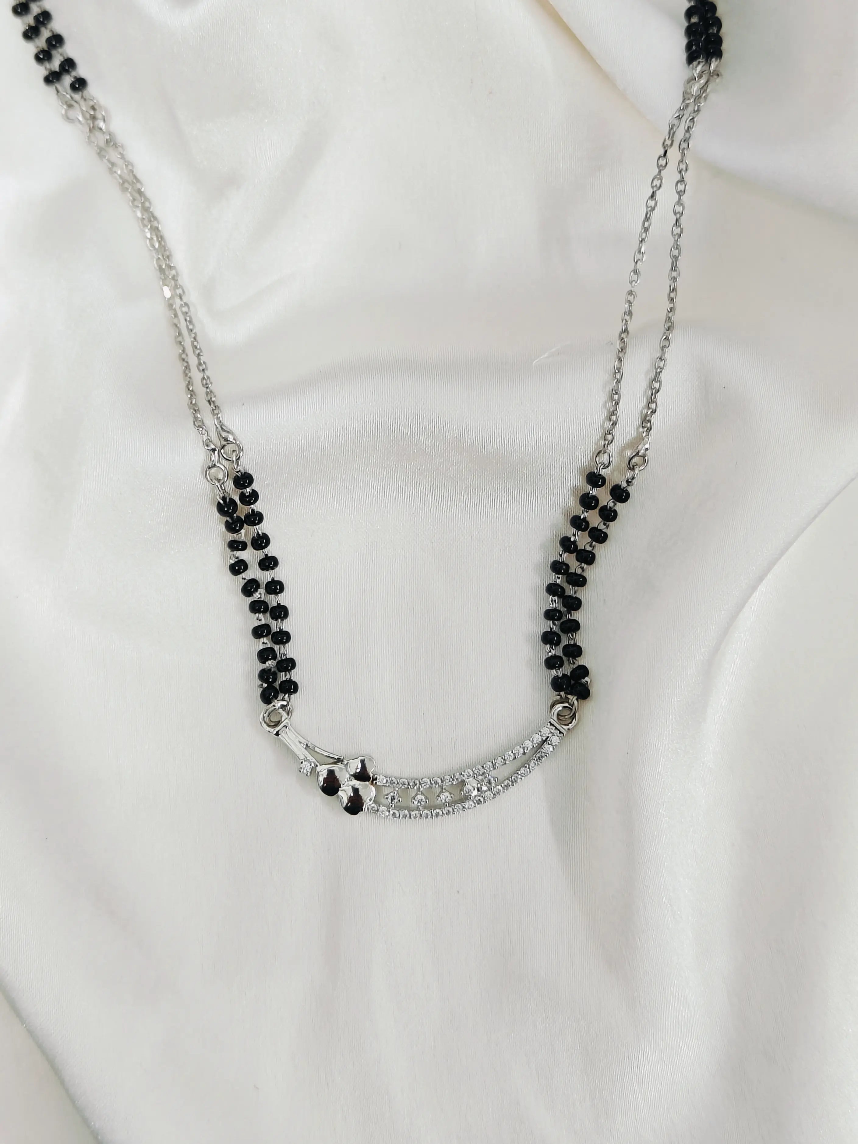 Necklace with black beads and silver chain on a white background